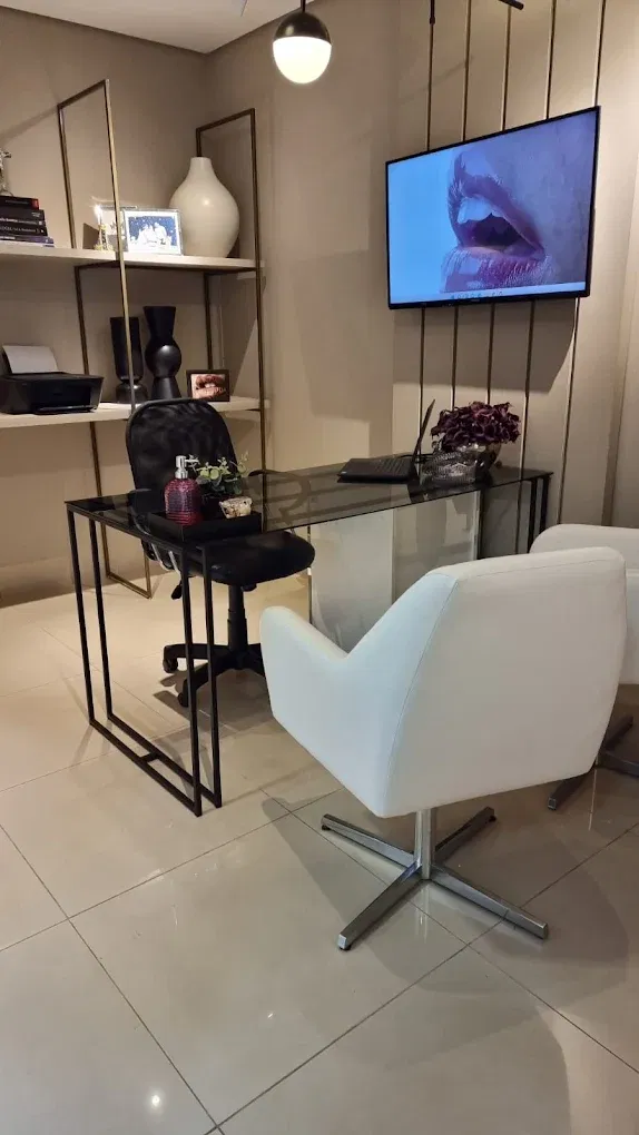 Sala de atendimento bege da Odontologia Faciale com mesa de vidro e televisão